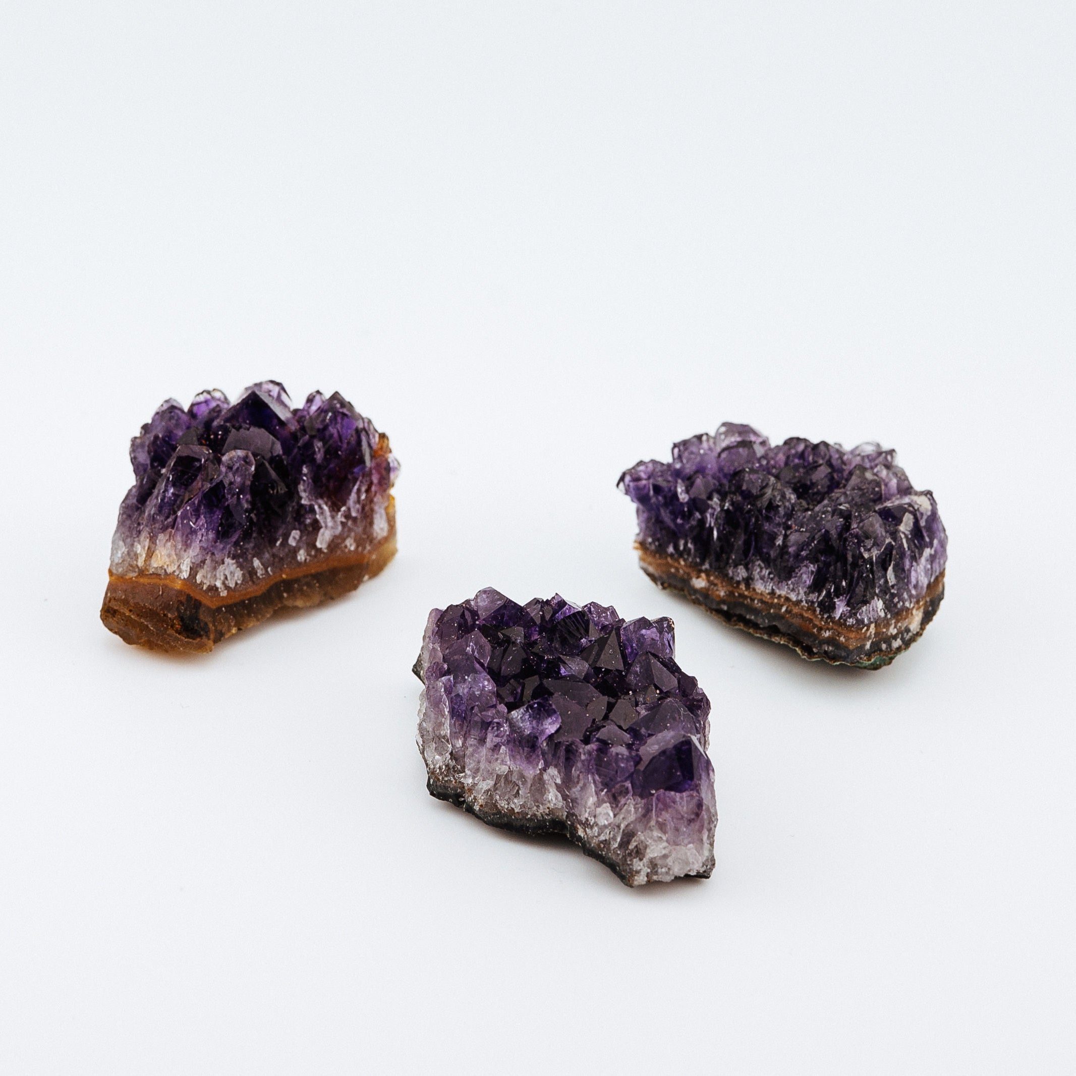 Three purple crystal formations on a white background