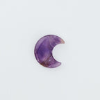 Purple moon-shaped crystal on a white background
