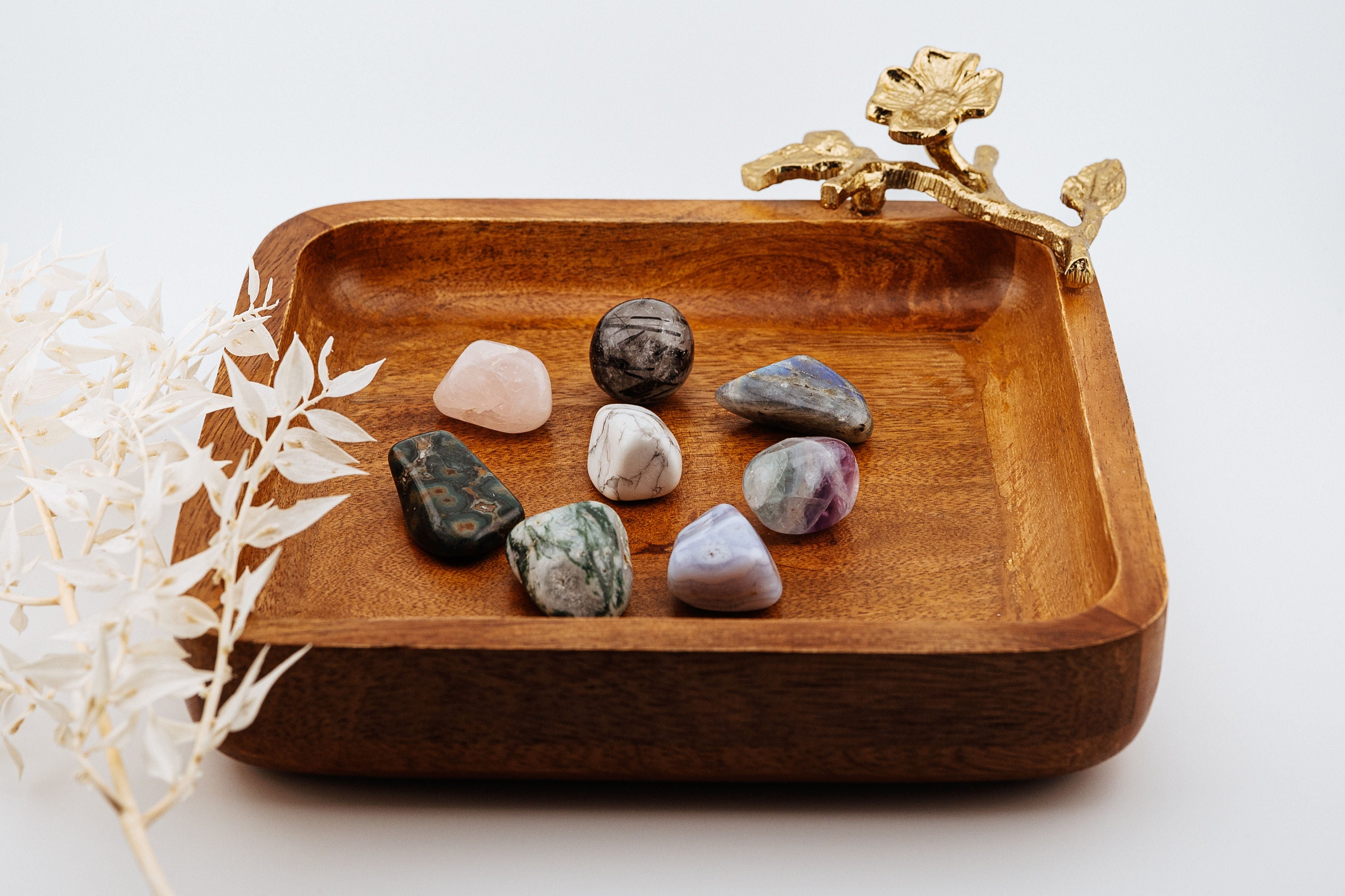 Wooden tray with decorative elements and stones on a white background
