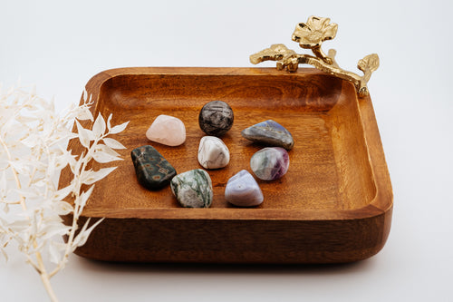 Wooden tray with decorative elements and stones on a white background