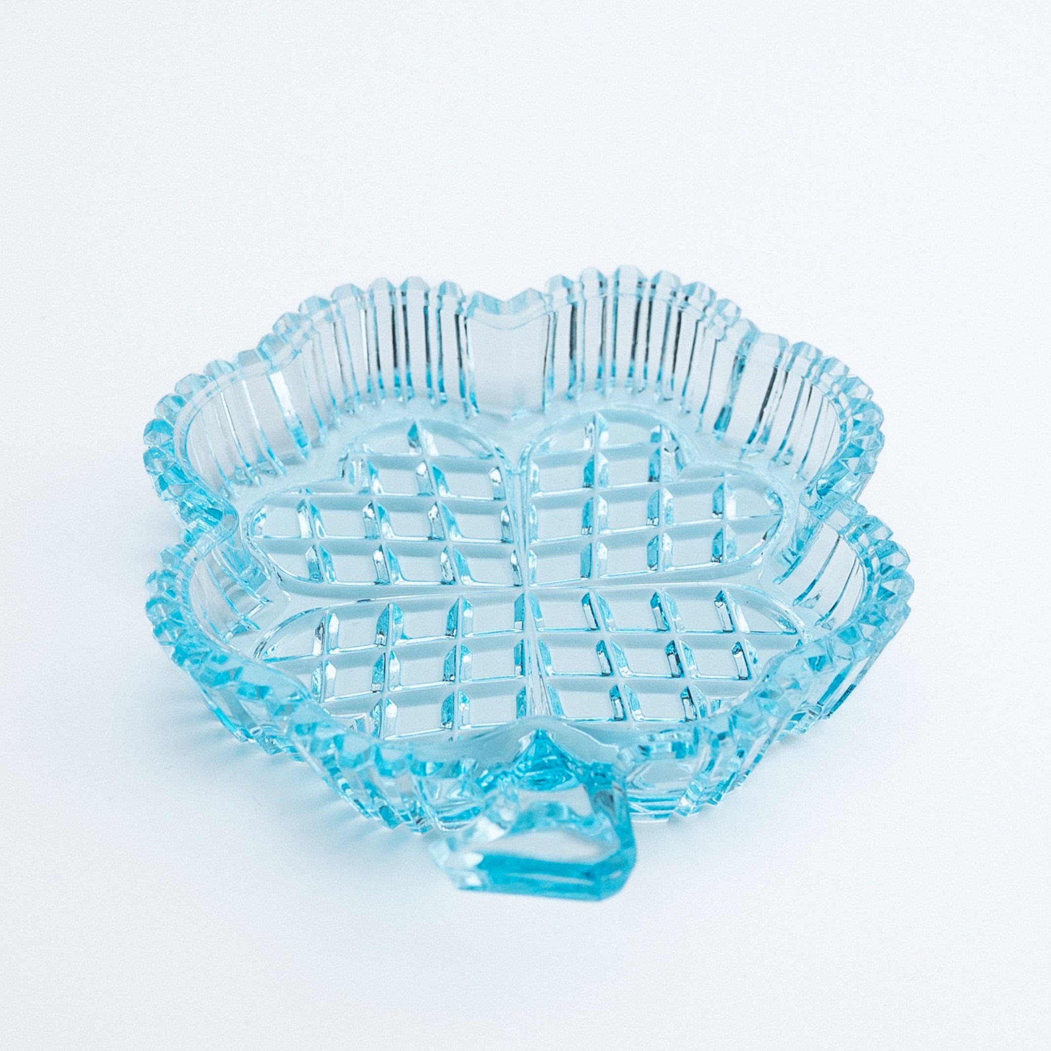 Blue clover shaped glass dish on a white background