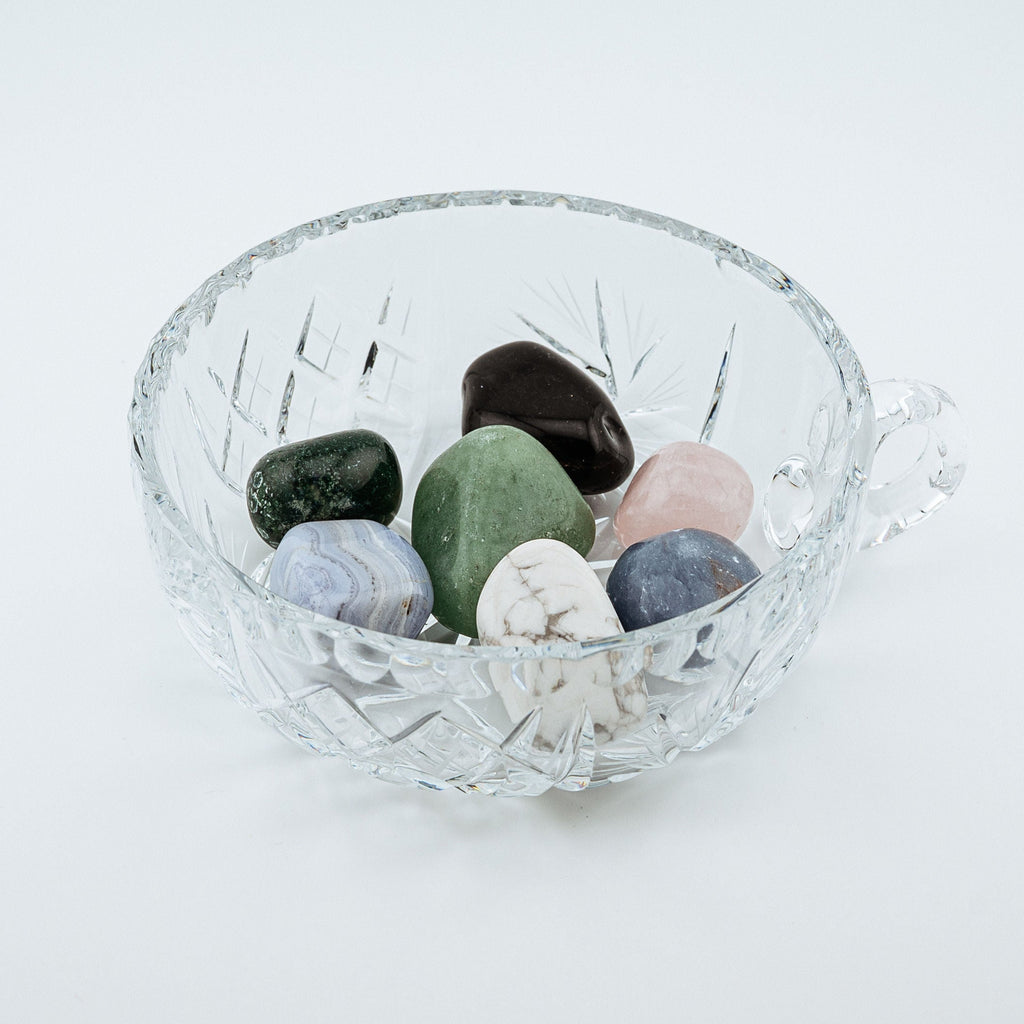 Clear glass bowl with multicolored stones on a white background