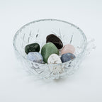 Clear glass bowl with multicolored stones on a white background