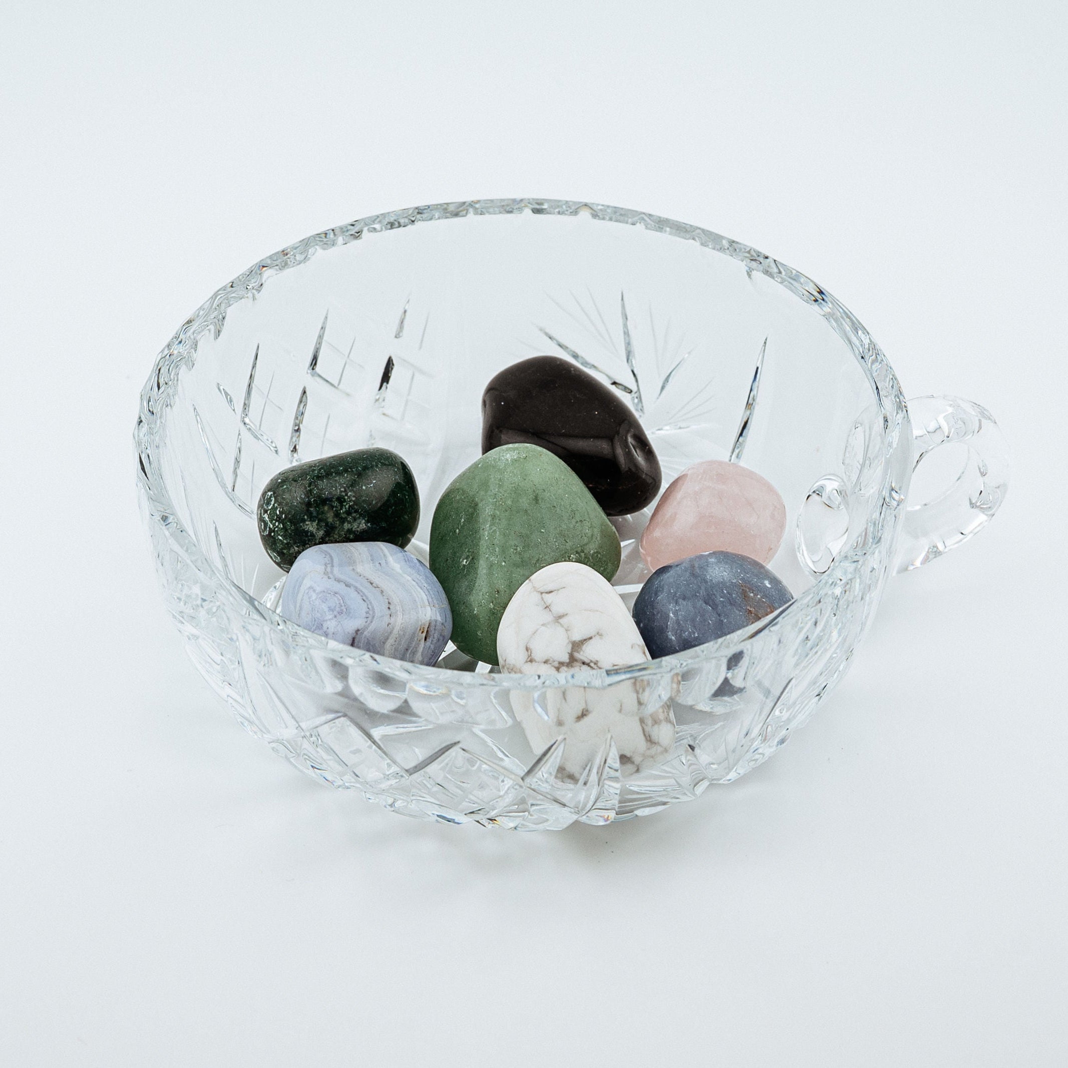Clear glass bowl with multicolored stones on a white background