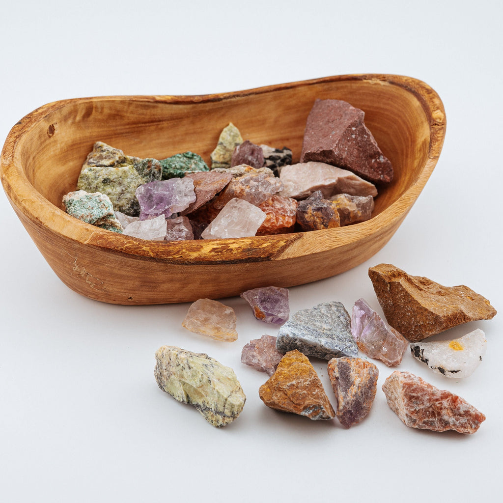 Wooden bowl filled with various colorful crystals on a white background