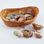 Wooden bowl filled with various colorful crystals on a white background