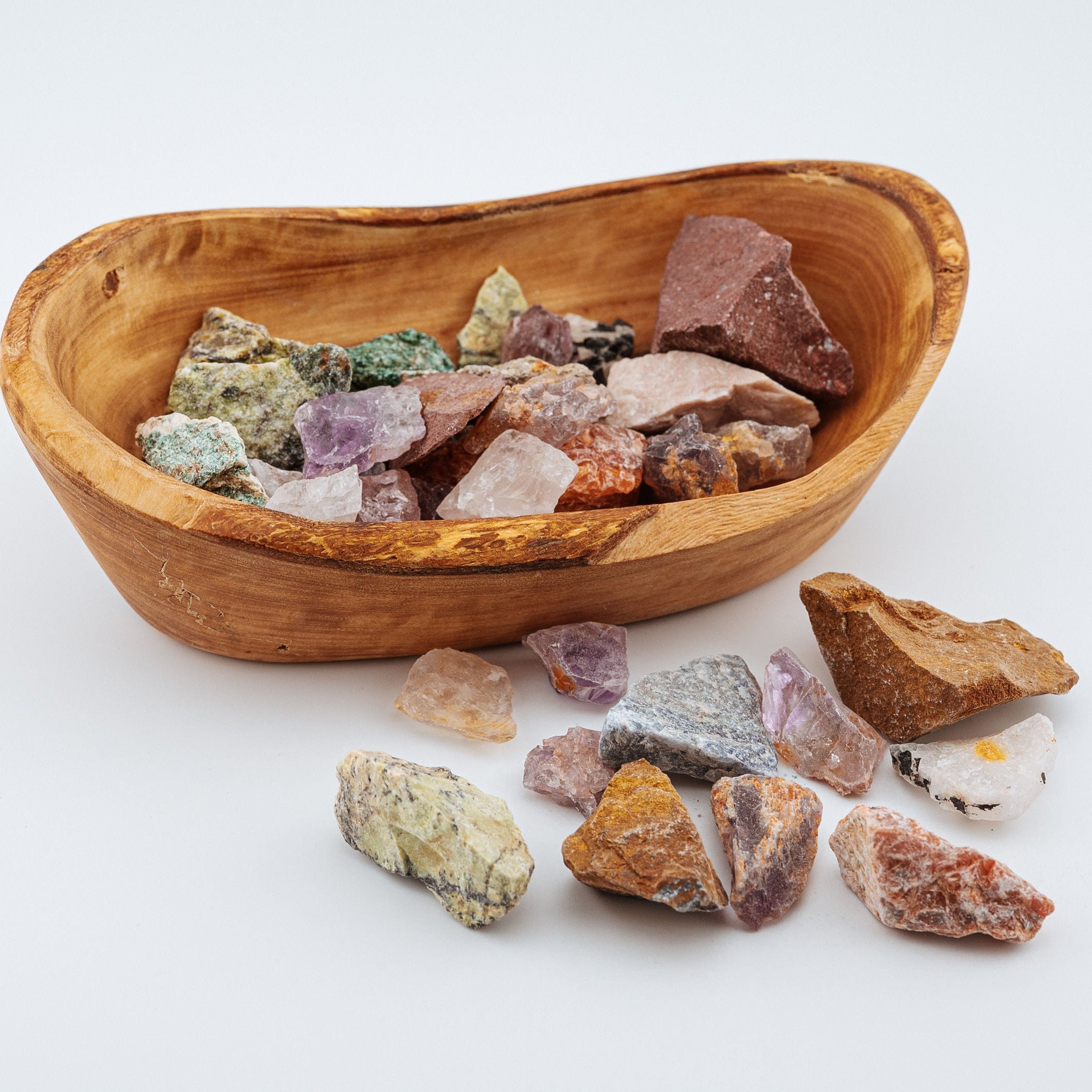 Wooden bowl filled with various colorful crystals on a white background