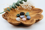 Wooden flower dish with colorful crystals and eucalyptus leaves on a white background