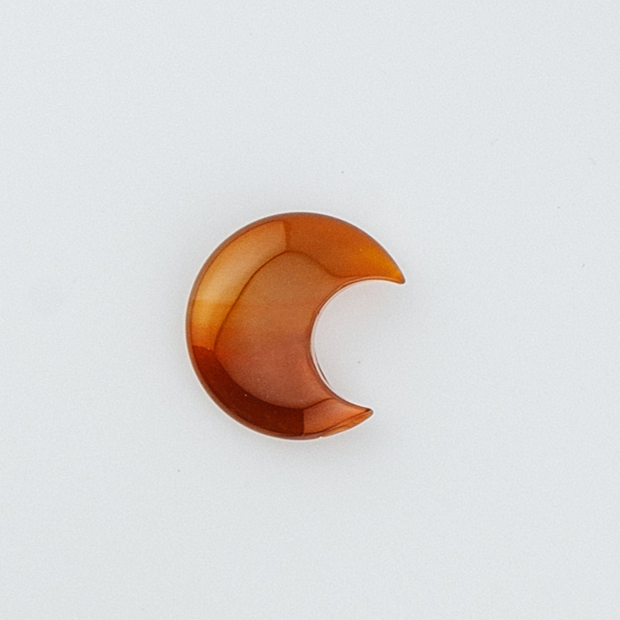 Orange crescent moon-shaped crystal on a white background