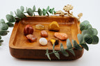 Wooden tray with crystals and a gold frog figurine on a white background