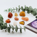 Set of colorful stones arranged on a white surface with eucalyptus leaves and a card.