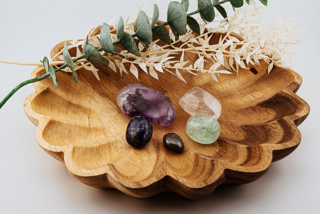 Wooden bowl with decorative stones and greenery on a light background