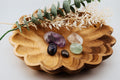 Wooden bowl with decorative stones and greenery on a light background