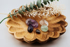 Wooden bowl with decorative stones and greenery on a light background