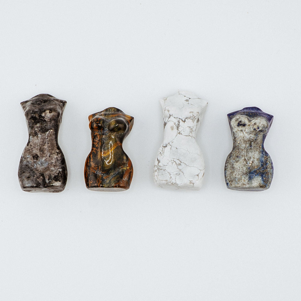 Four small stone figurines women's bodies on a white background