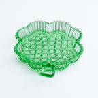 Green glass clover shaped dish with a textured surface on a white background