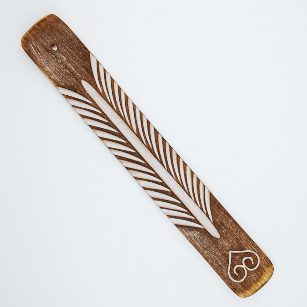 Wooden paddle with feather and heart design on a white background