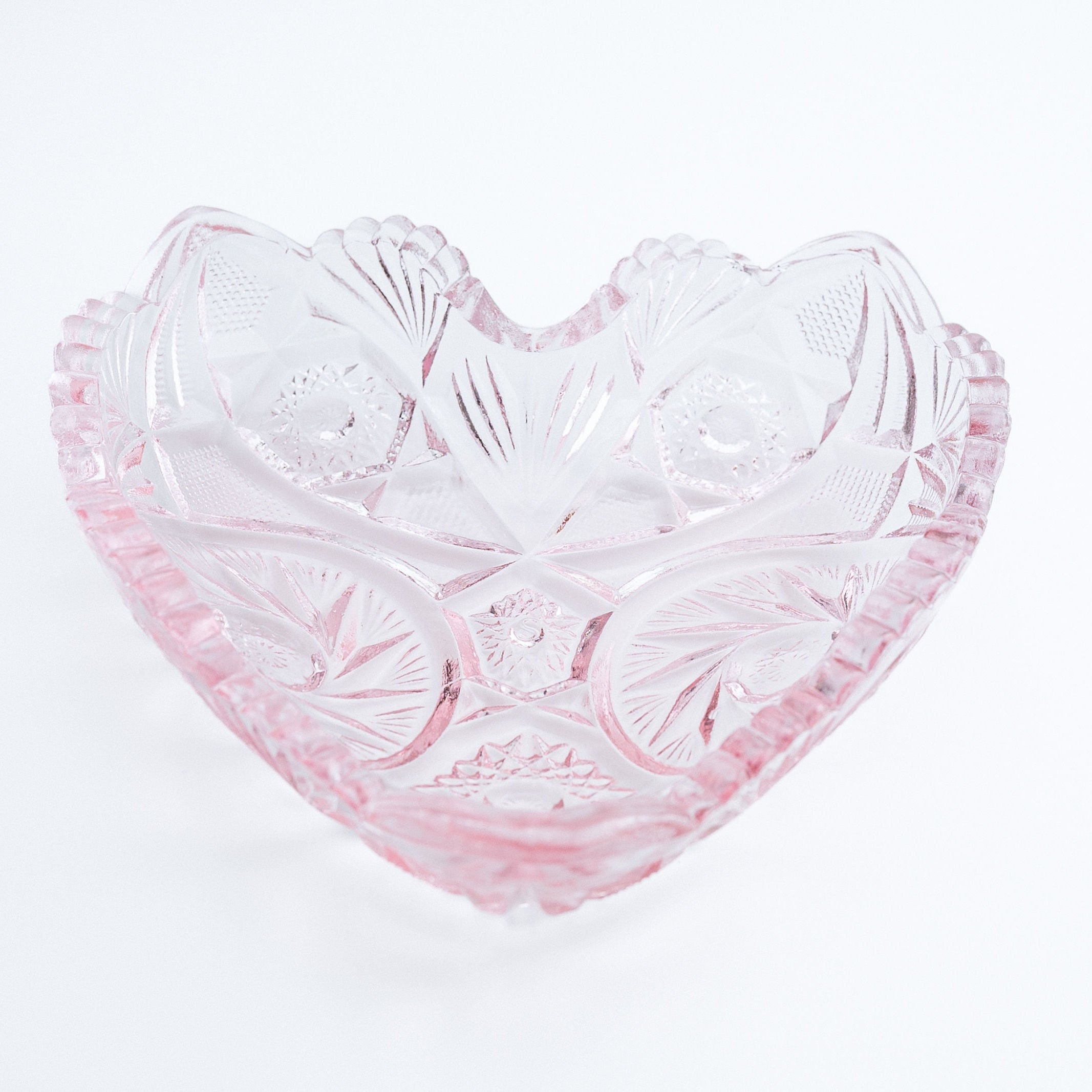 Heart-shaped glass bowl with pink tint on a white background