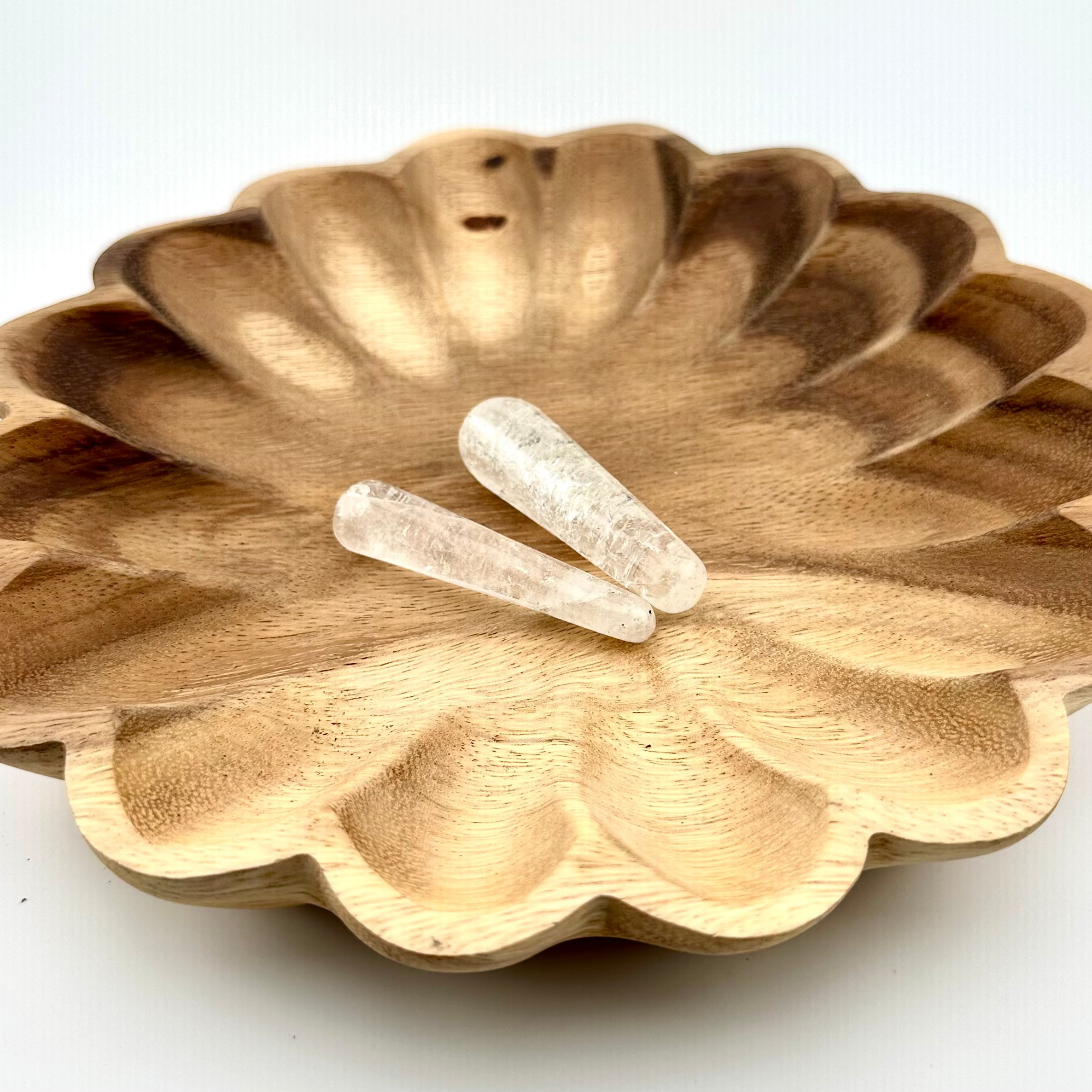 long wand shaped clear stones on wooden bowl
