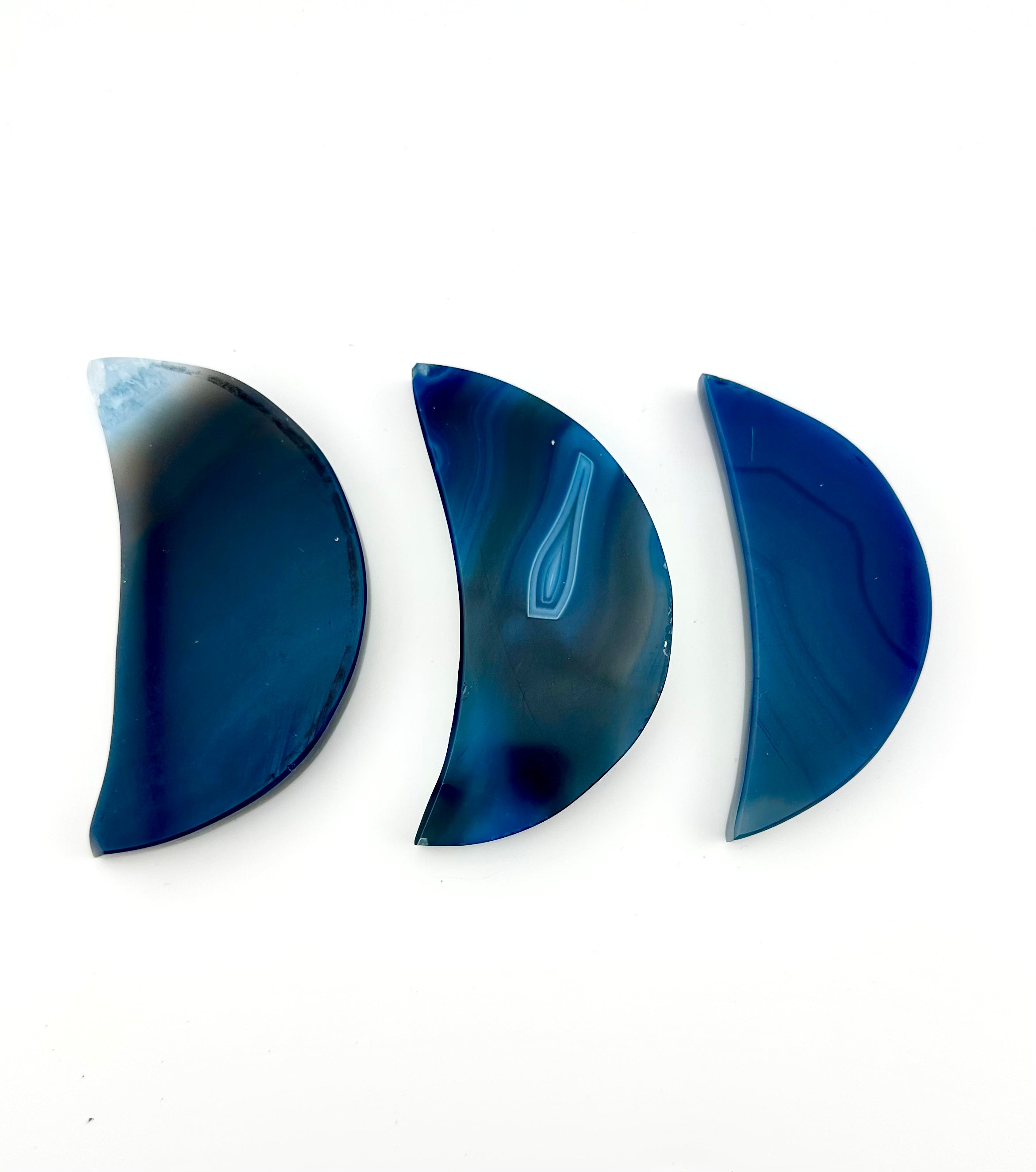 Three polished crescent-shaped blue agate gemstone cabochons arranged horizontally on a plain white background.