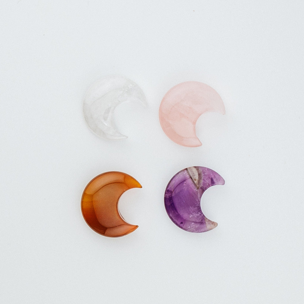 Set of three semi-precious stone moon carvings on a white background