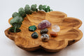 Wooden leaf-shaped dish with crystals and eucalyptus on a white background