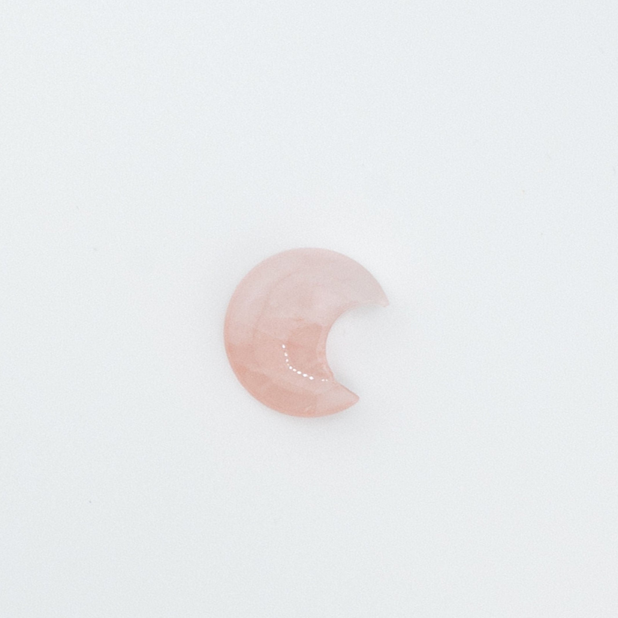 Pink crescent moon-shaped stone on a white background