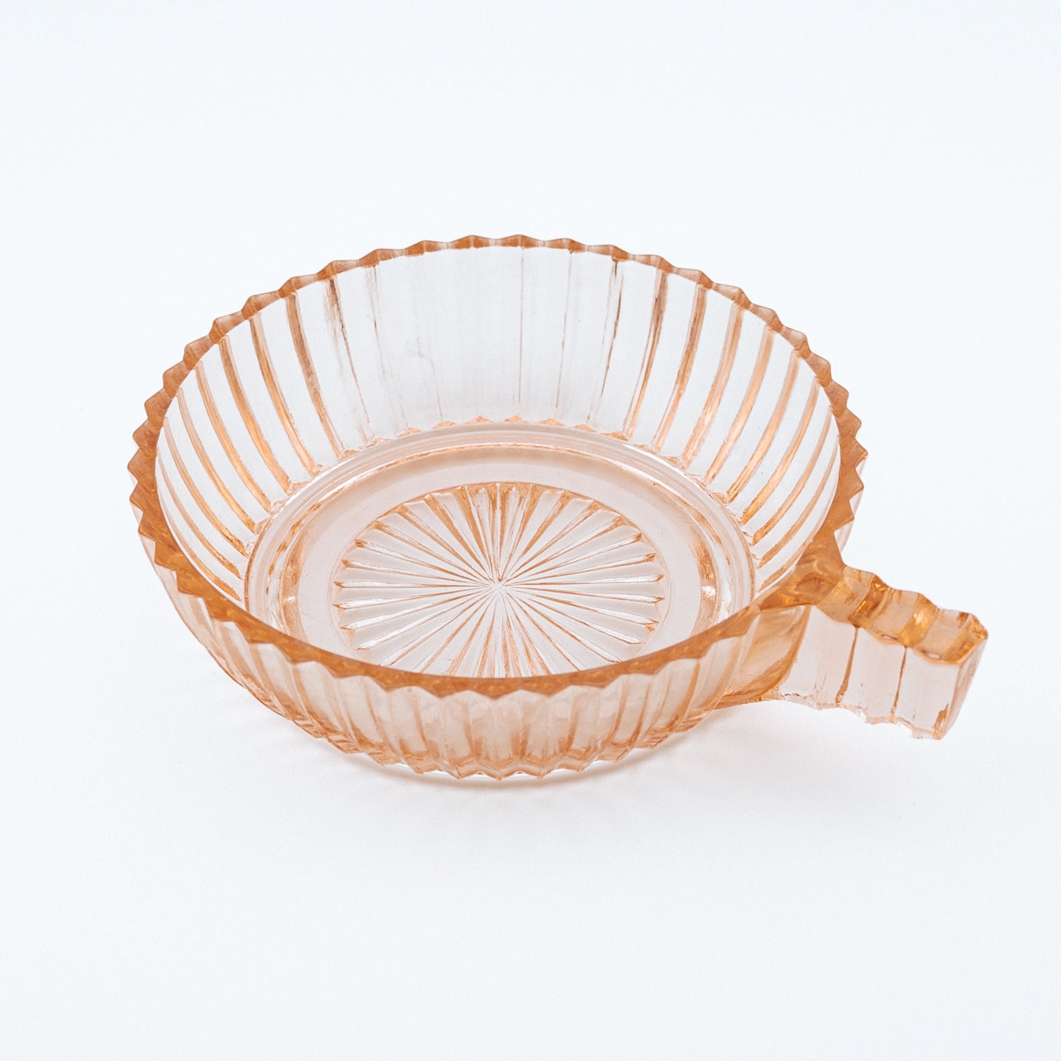 Pink glass bowl with a handle on a white background