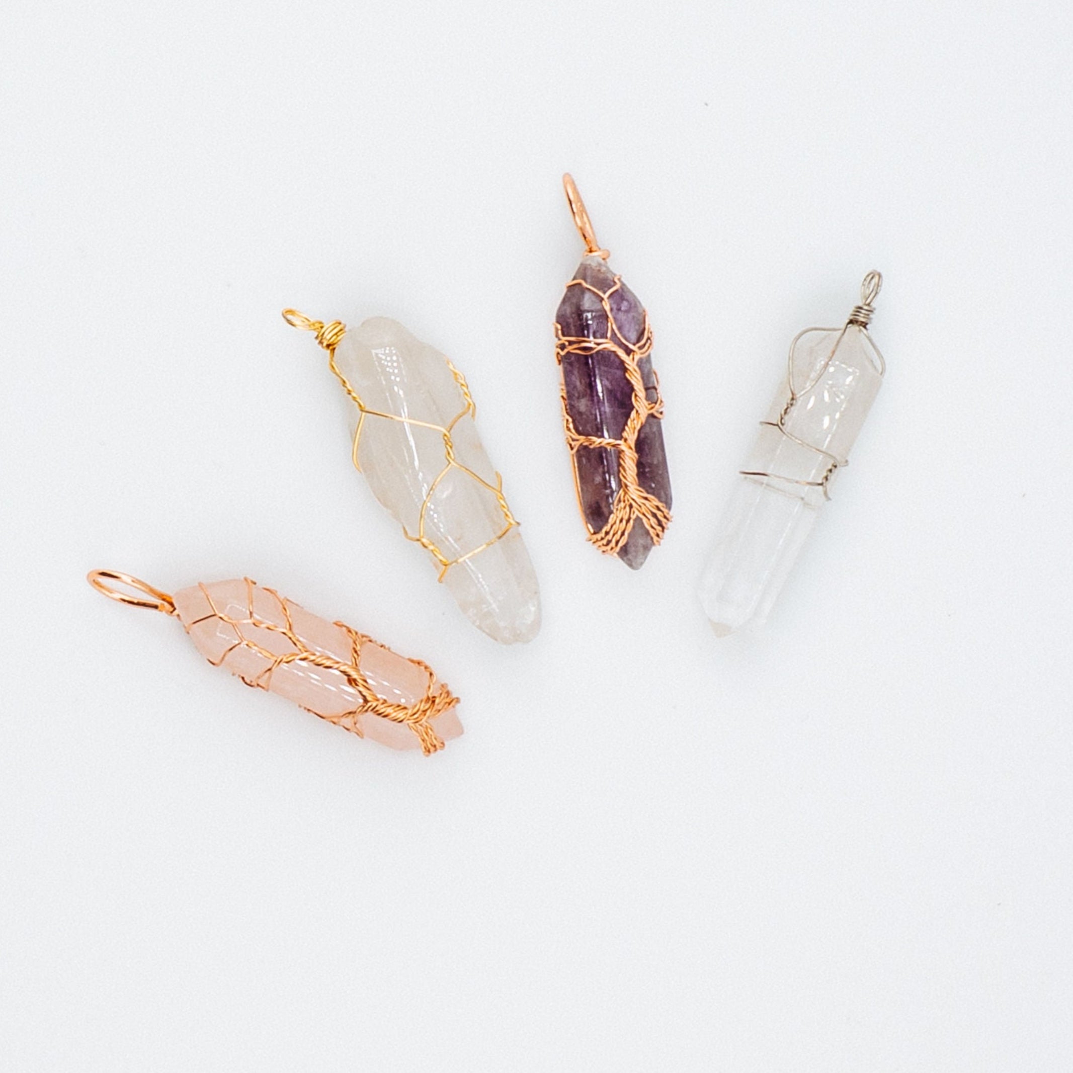 Four different crystal necklace pendants on a white background
