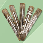Five wooden sticks with white patterns on a green background